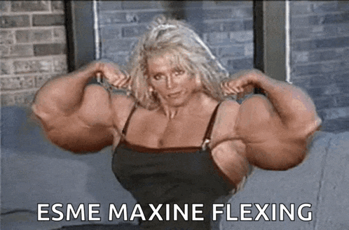 a very muscular woman in a black dress is flexing her muscles on a couch .