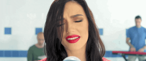 a woman singing into a microphone with red lipstick