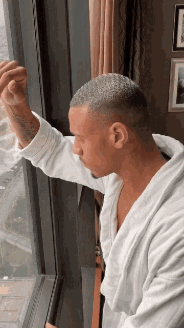 a man in a bathrobe looks out a window