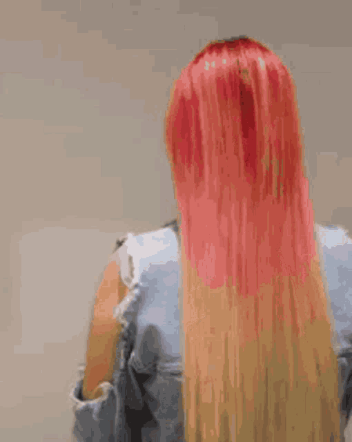a woman with red hair is wearing a blue denim jacket and red lipstick .