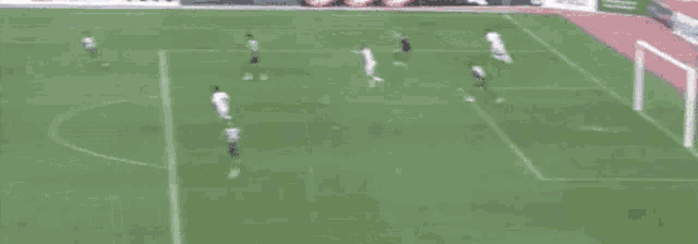 a blurred image of a soccer field with a few players and a goal