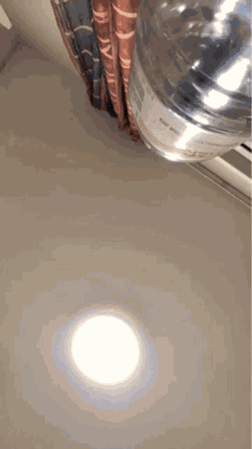 a bottle of water is sitting on a table next to a curtain