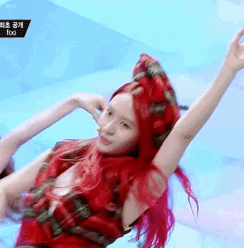 a woman with red hair is dancing in front of a blue background