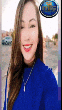 a woman wearing a blue shirt and a necklace is smiling in front of a nik's logo