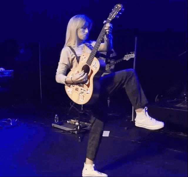 a woman playing a guitar with stickers on it including one that says ' i love you '