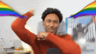 a man in a red sweater is holding a rainbow flag in his hands