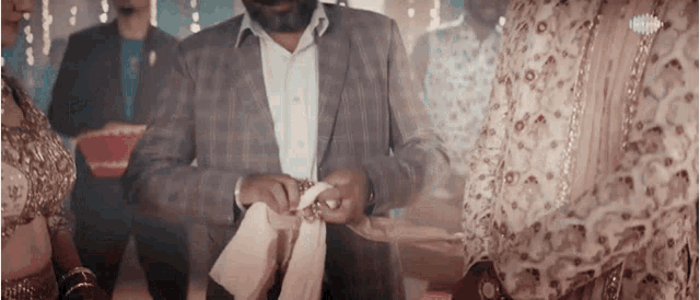 a man in a suit is putting a ring on a woman 's finger ..