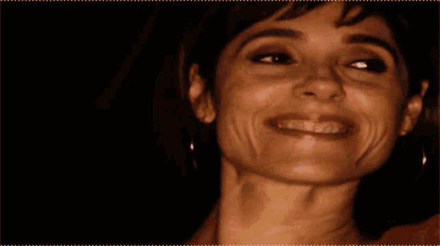 a close up of a woman 's face smiling with a dark background