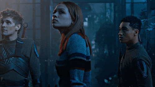 a woman in a blue sweater stands next to two other people