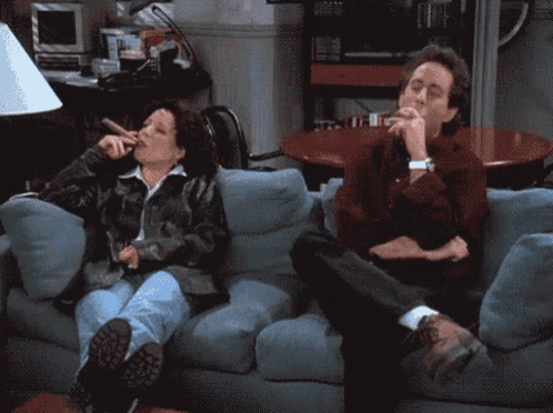 a man and a woman sit on a couch smoking