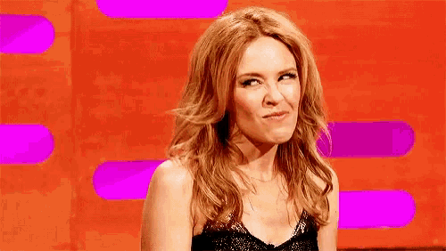 a woman in a black dress is making a funny face while sitting on a stage .