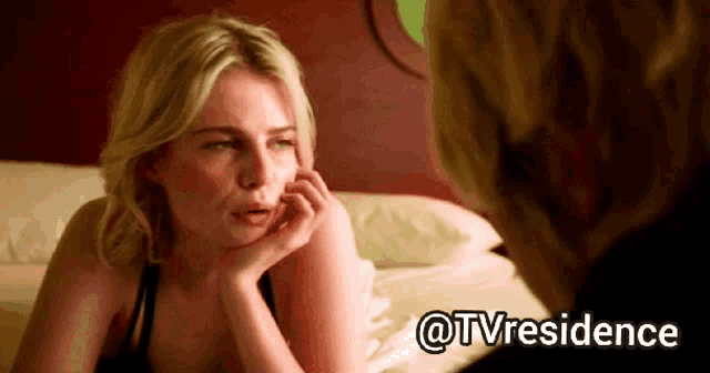 a woman sits on a bed with her hand on her face and the words @tvresidence behind her