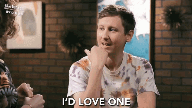 a man says i 'd love one while sitting in front of a brick wall