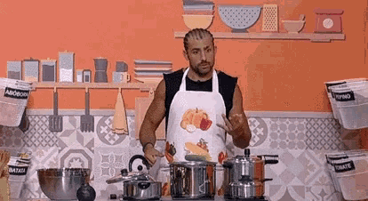 a man wearing an apron is standing in a kitchen cooking .
