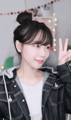 a girl in a denim jacket is making a peace sign