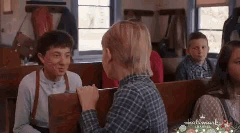 a group of children are sitting in a church talking to each other and looking at each other .