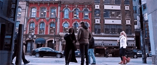 a group of people are walking down a city street in front of a building that says park