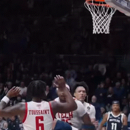 a basketball player wearing a toussaint jersey tries to block a shot