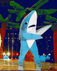 a blue and white shark costume is standing on a stage