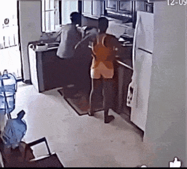 a man and a woman are standing in a kitchen with the time of 12:09