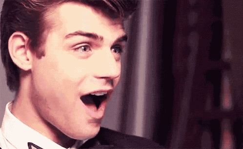 a young man in a suit and bow tie is making a surprised face .