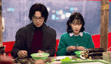 a man and a woman are sitting at a table eating from bowls .