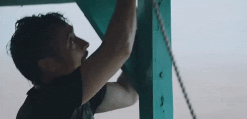 a man is climbing up a wooden post on a rope .