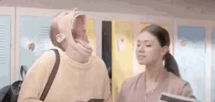a man with his mouth open is standing next to a woman in a locker room .