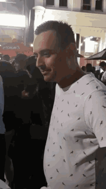 a man in a white shirt with black birds on it