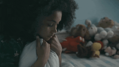 a woman is laying on a bed with stuffed animals in the background