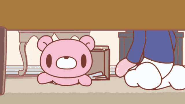 a pink teddy bear sits under a table with a box underneath it