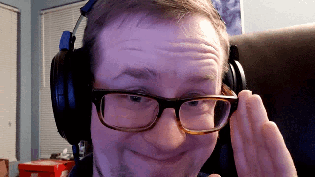 a man wearing headphones and glasses looks at the camera