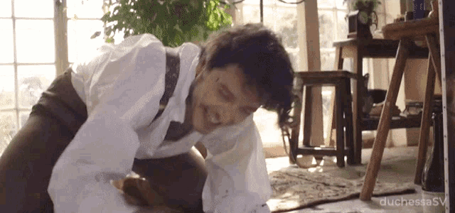 a man in a white shirt is kneeling down and smiling in a room