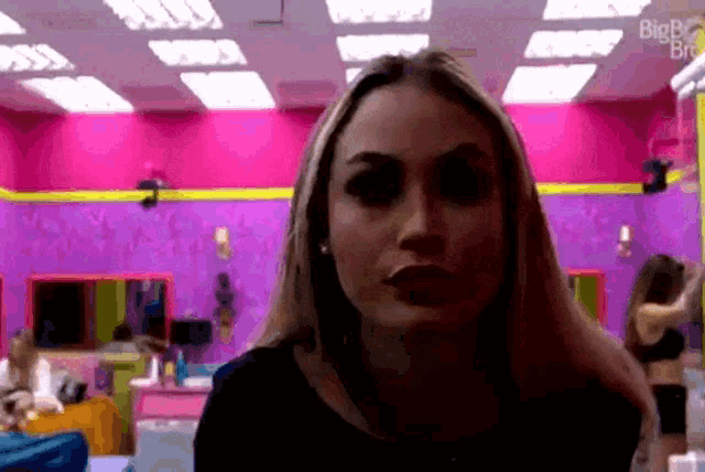 a woman is standing in a room with pink walls and a sign that says bigb