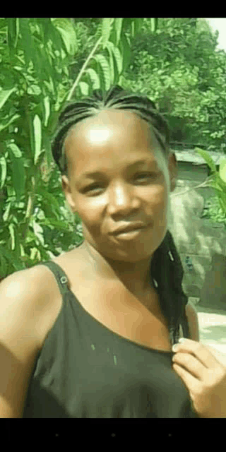 a woman in a black tank top with braids on her head