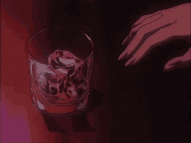 a hand is pouring a red liquid into a glass with a skull on it