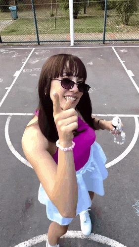 a woman wearing sunglasses is giving a thumbs up sign