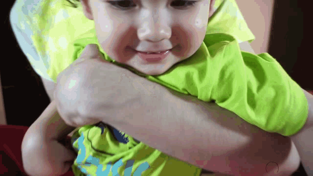 a little boy in a green shirt is being held by a woman