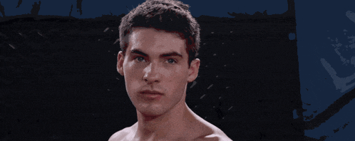 a shirtless man stands in a boxing ring