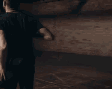 a man in a black shirt is standing in a dark room .