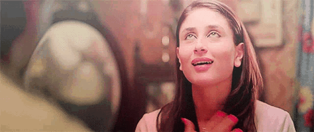 a woman with red nails is smiling and looking up at something .