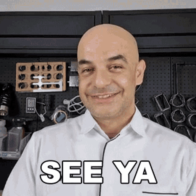a bald man wearing a white shirt with the words see ya written on it