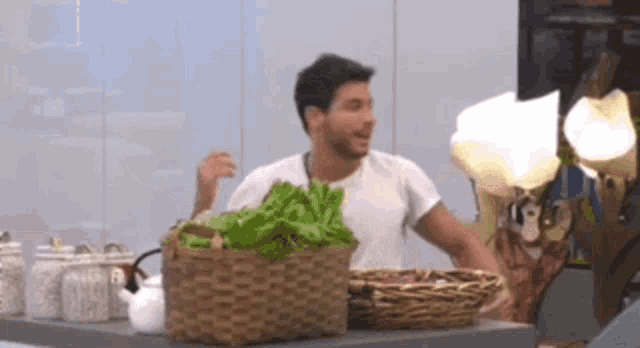 a man in a white shirt is standing in front of a table with baskets of lettuce .
