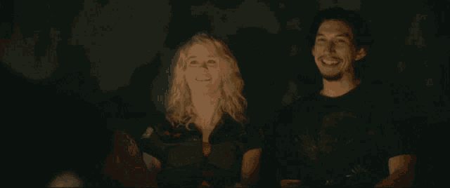 a man and woman are laughing together in a dark room
