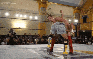 a couple of men are wrestling in a wrestling ring .