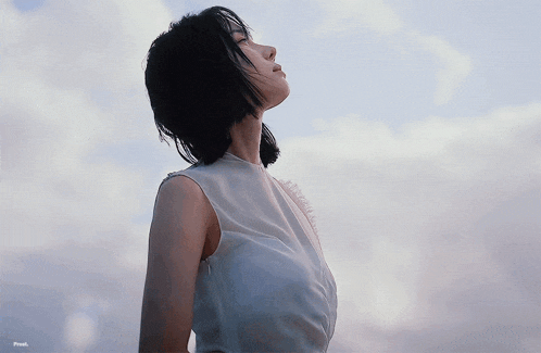 a woman in a white shirt looks up at the sky