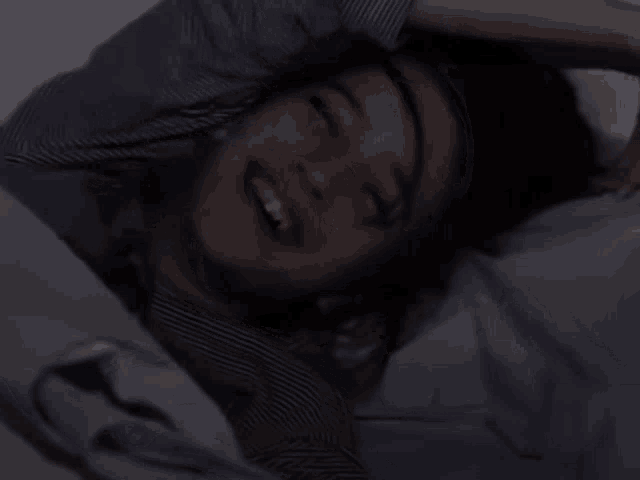 a woman is laying in bed with her eyes closed and her mouth open