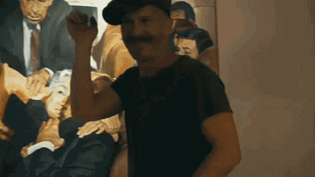 a man with a hat and mustache is standing in front of a painting
