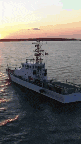 a large boat is floating in the ocean at sunset .