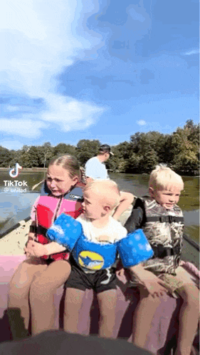 a group of young children are sitting in a boat on a lake .
